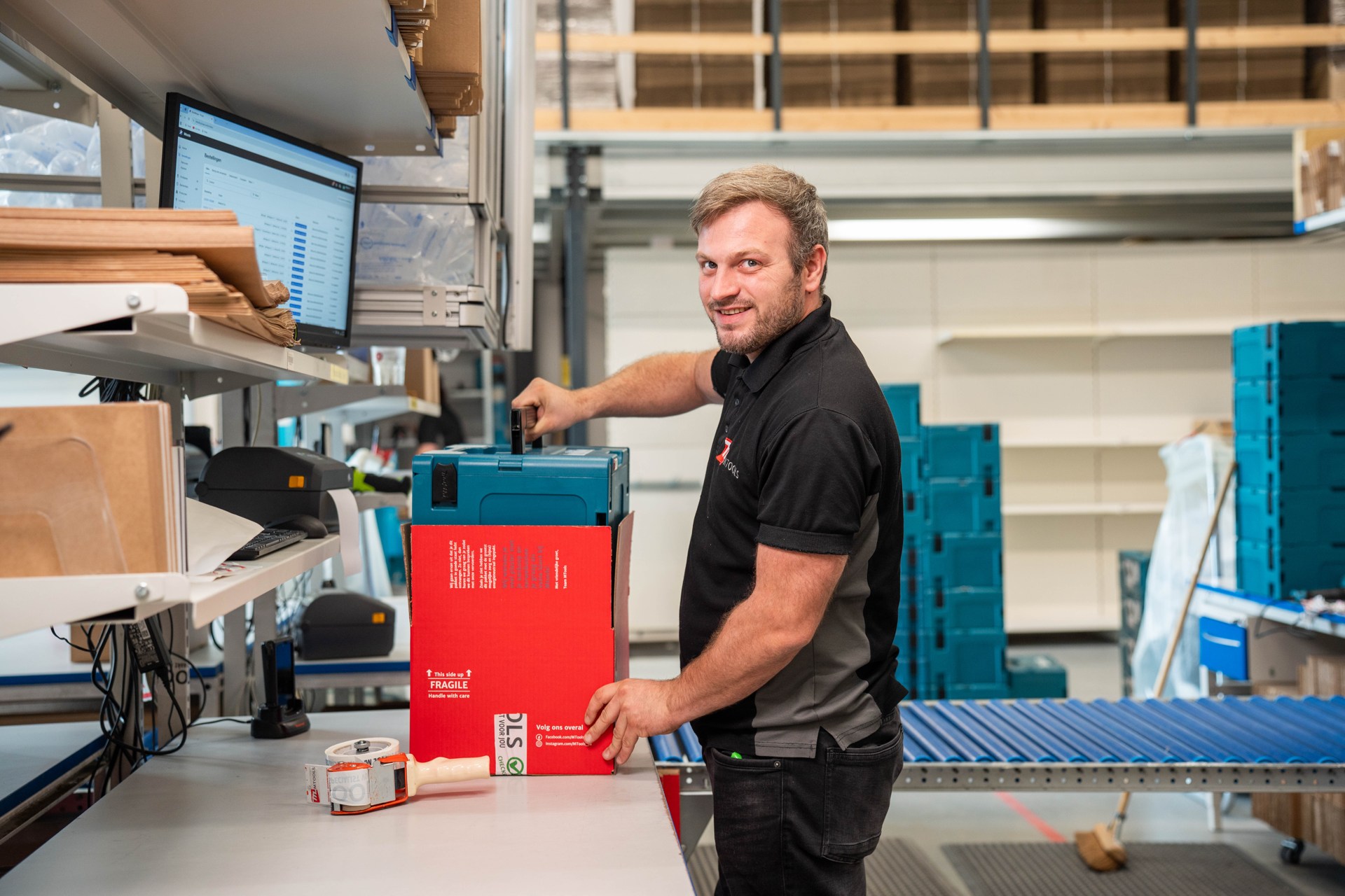 Een medewerker bij de inpakwerkplek in het voormalige Mtools-magazijn